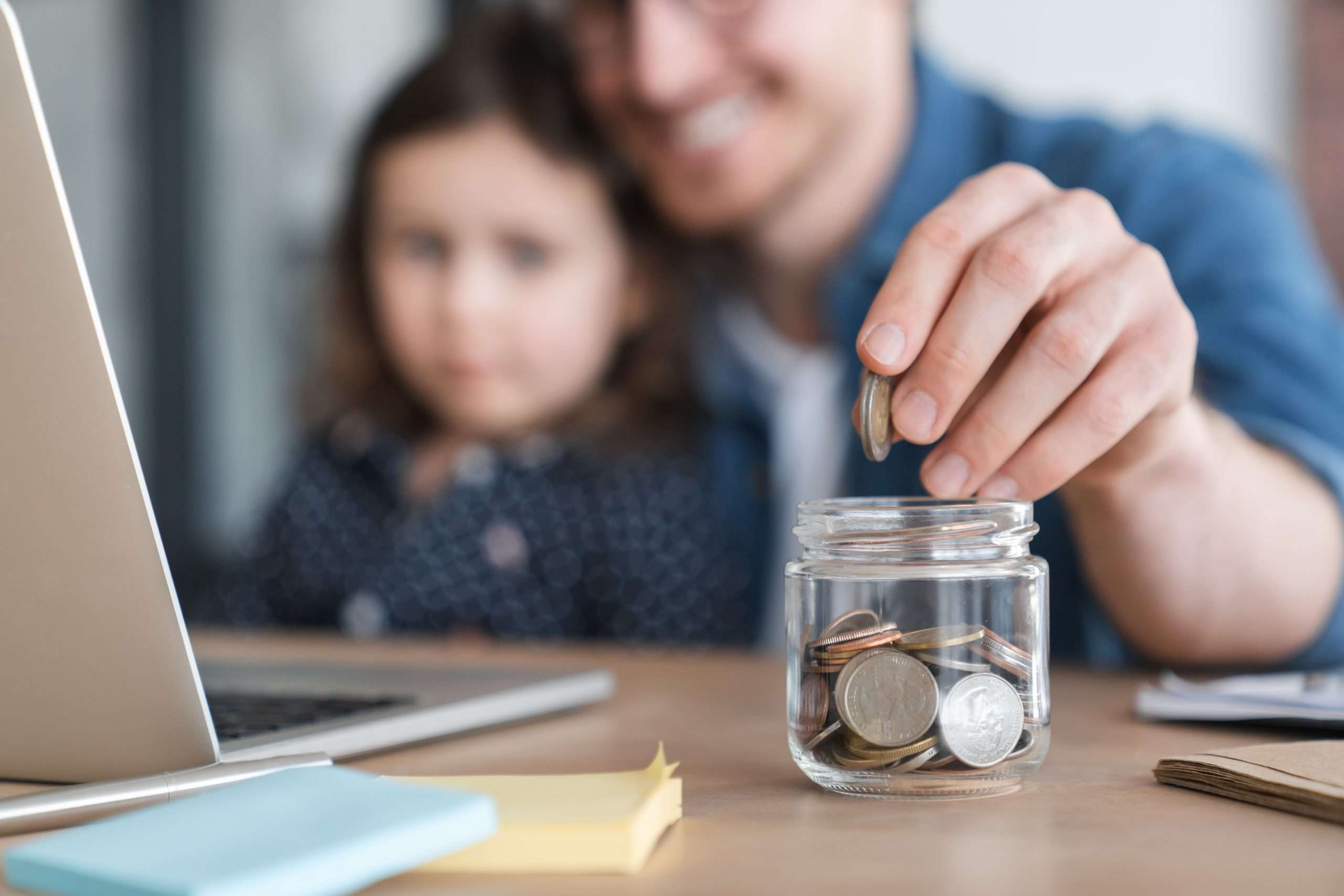 Man putting money into jar for daughter